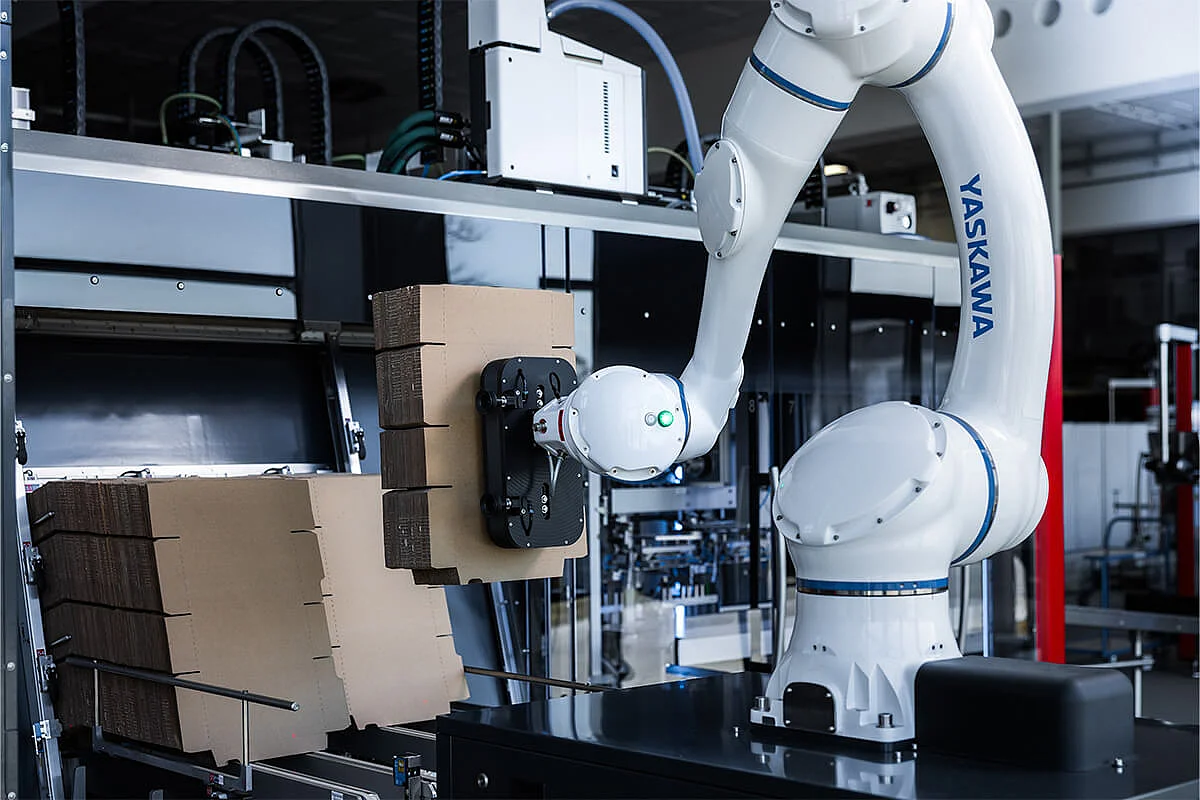SOMIC CoboLoad - Cobot belädt das Kartonmagazin einer SOMIC 434 Verpackungsmaschine mit Kartonzuschnitten